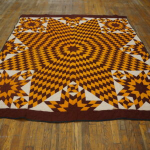 Low-profile textile featuring a geometric star pattern in brown, gold, and cream on rustic wood flooring.