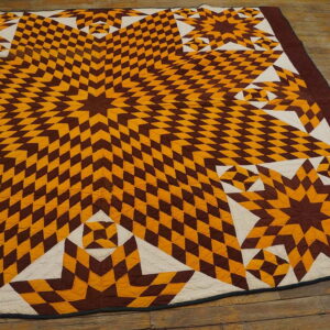 Flat-weave brown, gold, and cream starburst textile pattern resting on rustic wood plank flooring.