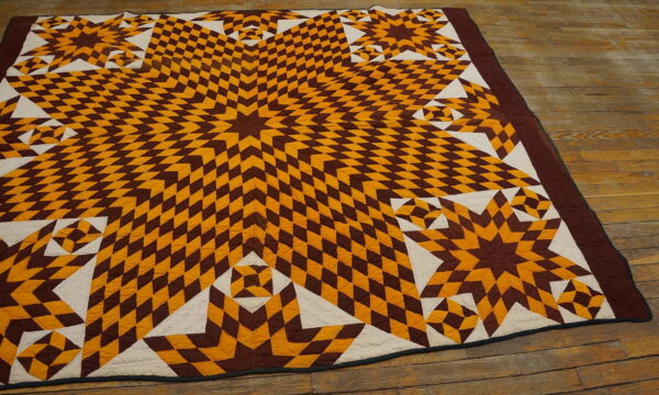 Flat-weave brown, gold, and cream starburst textile pattern resting on rustic wood plank flooring.