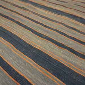 Flatweave rug with diagonal stripes in dark blue, dusty light blue, and thin rust orange accents.