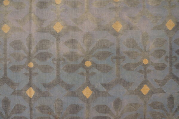Low-pile blue rug featuring a repeating gray botanical design accented with pale gold diamonds.