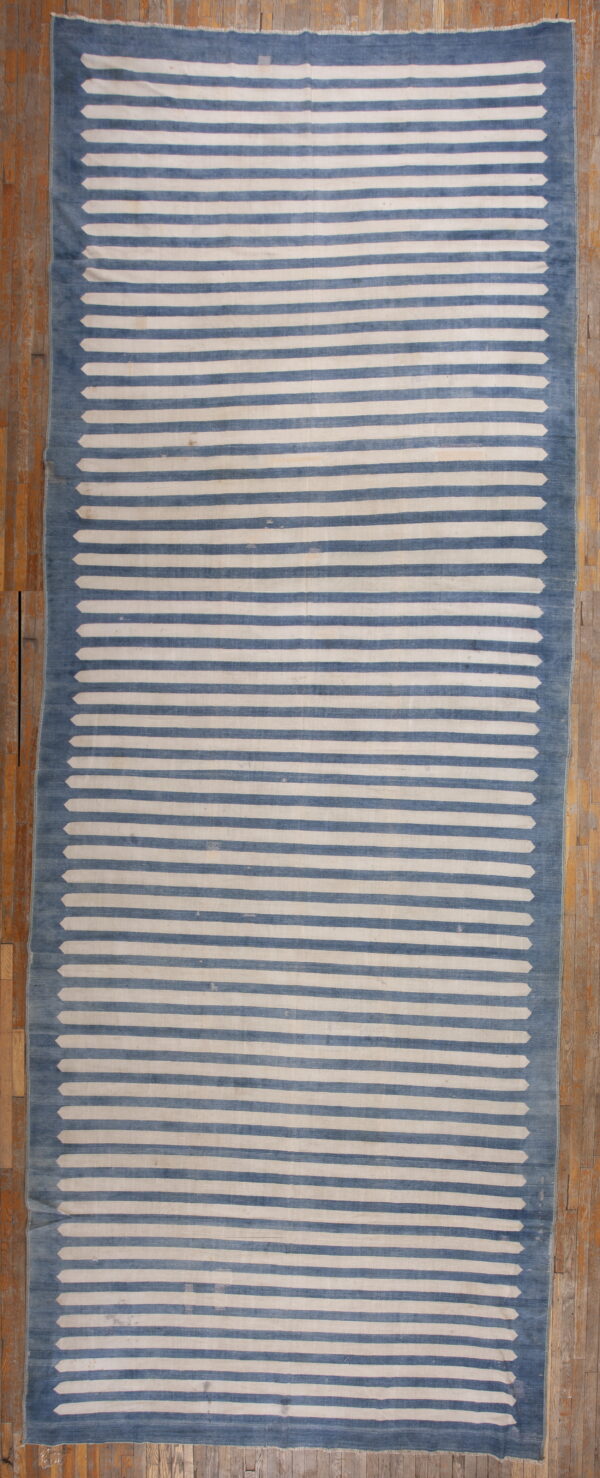 Low-pile rug with blue and off-white horizontal stripes tapering to points at the blue border.
