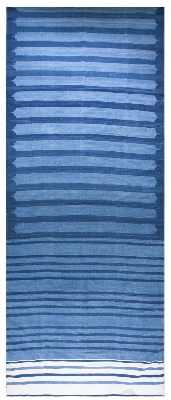 Blue striped flatweave rug featuring staggered edges and a thick white striped border along the bottom.