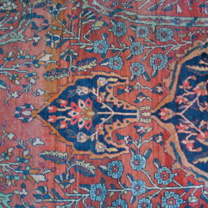 Detailed close-up of a rug featuring an intricate floral medallion in rust red and navy blue.