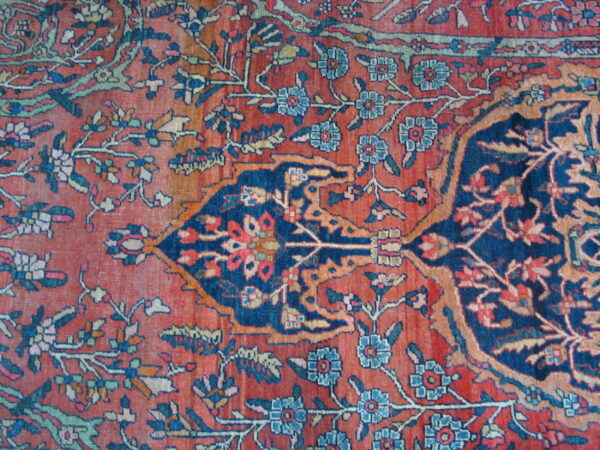Detailed close-up of a rug featuring an intricate floral medallion in rust red and navy blue.