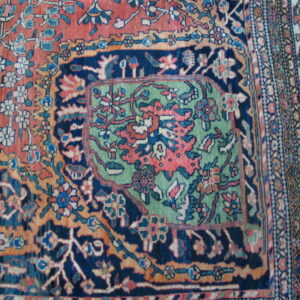 A detailed low-pile rug section featuring rust, navy, and mint green floral designs and multiple borders.