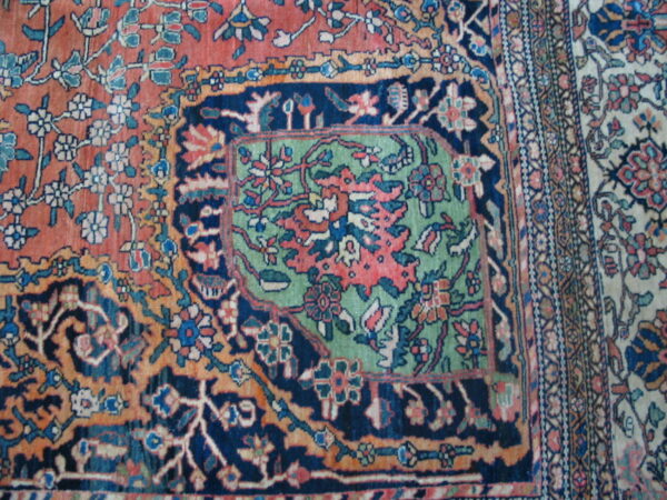 A detailed low-pile rug section featuring rust, navy, and mint green floral designs and multiple borders.