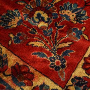 Close-up of a medium-pile rug featuring red and gold borders surrounding navy floral motifs.