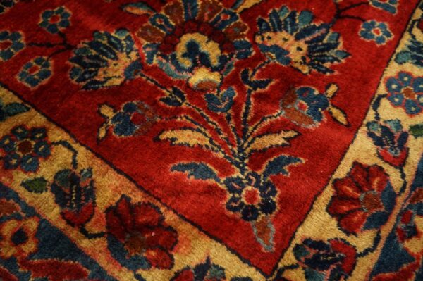 Close-up of a medium-pile rug featuring red and gold borders surrounding navy floral motifs.