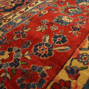 A rug surface detail in red, navy blue, and gold, featuring intricate borders and floral designs.