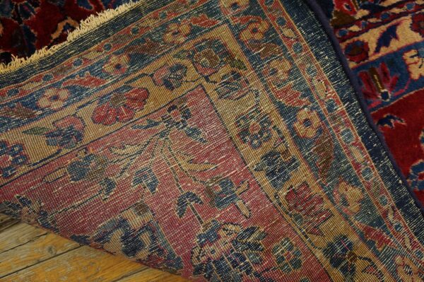 The detailed red, tan, and blue backing of a patterned rug is visible over worn wooden floors.