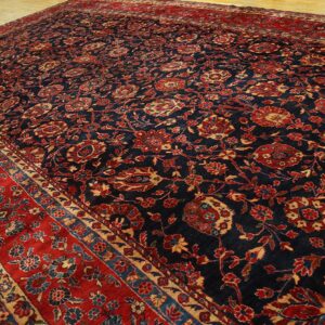 Traditional dark blue rug with dense red and gold floral patterns and a wide red border on wood flooring.