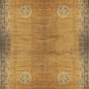 A gold low-pile rug with a tone-on-tone meander field pattern and four cream and blue corner medallions.