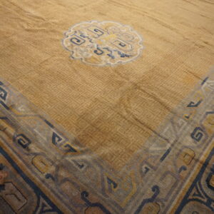 Gold rug with subtle geometric texture, a central blue medallion, and a wide multicolored border.