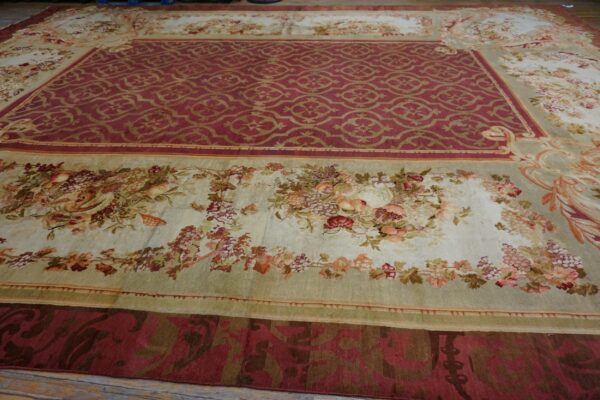 Large traditional rug featuring a red medallion field and wide light floral borders on wood planks.