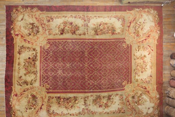 Cream and burgundy low-pile rug featuring a central trellis design and detailed fruit and floral borders.