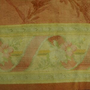 Muted coral rug features a wide border with pink floral patterns, pale green background, and yellow stripes.