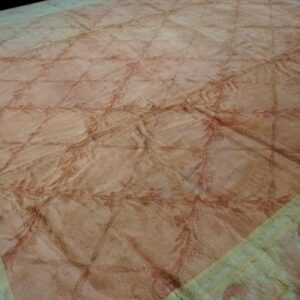 Wrinkled, low-pile rug with a blush field, reddish trellis pattern, and faded pale green border.