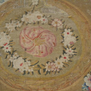 Distressed flatweave rug featuring a large faded pink rosette surrounded by a detailed white and green floral garland.
