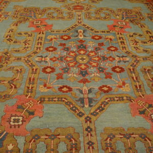 Ornate floral rug featuring a soft blue-green field accented by red, gold, and coral traditional motifs.