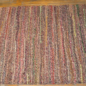 Textured runner rug with multicolored vertical braided segments lying on light wood planks.
