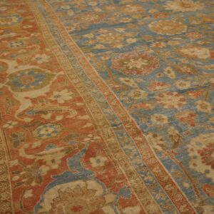 Distressed blue and terracotta traditional rug with floral motifs on light wood floors.