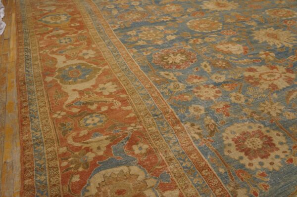Distressed blue and terracotta traditional rug with floral motifs on light wood floors.