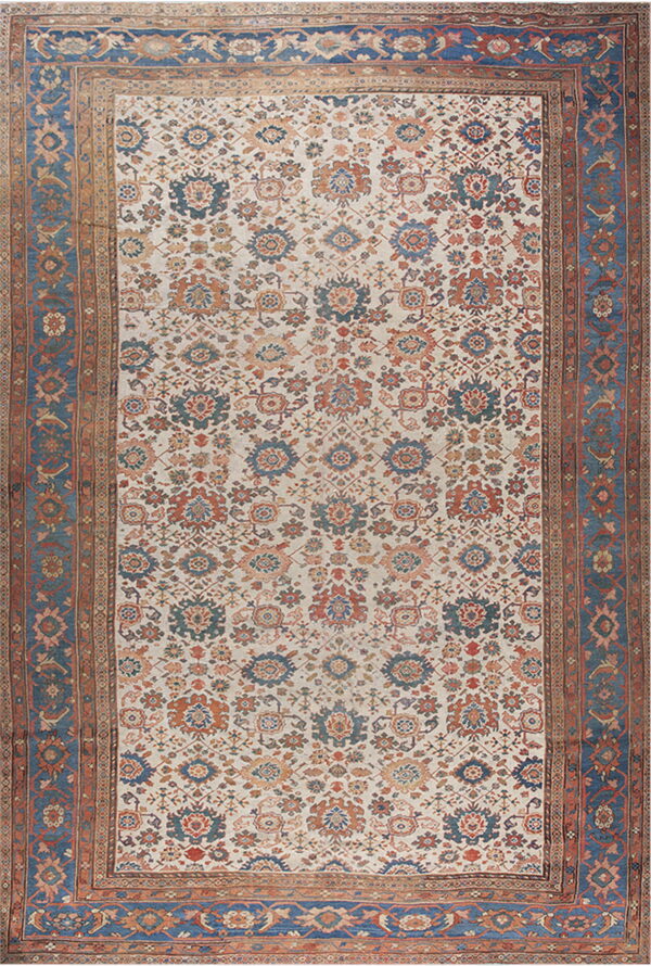 Cream rug with dense rust and blue all-over floral pattern and wide indigo outer borders.