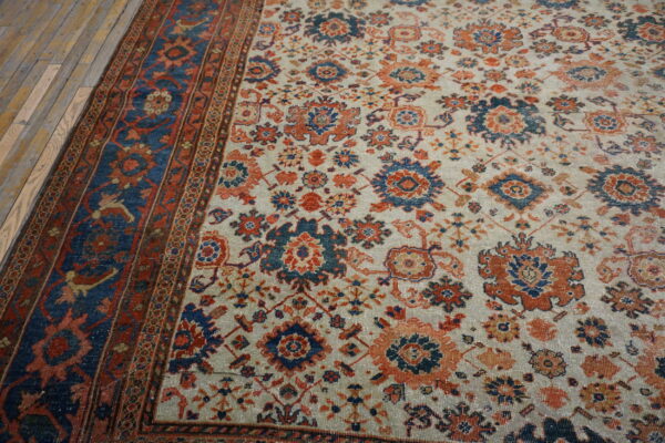Floral pattern rug in indigo, rust, and cream colors, with a distressed border on wood plank flooring.
