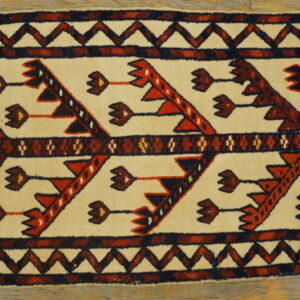 Geometric flatweave runner featuring a cream field with stylized red and dark brown tribal motifs on wood flooring.