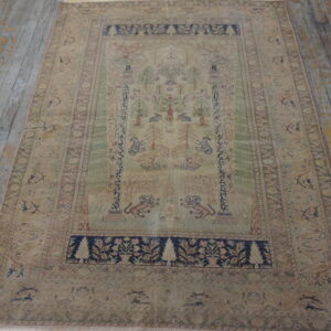 Muted pictorial rug featuring fauna and flora, with navy accents, placed on distressed gray wood flooring.