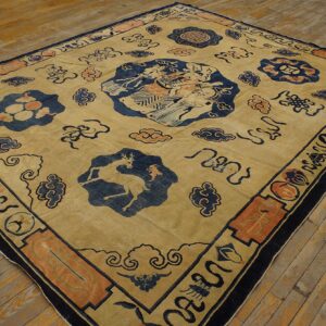 Tan square rug featuring blue medallions, rust accents, cloud patterns, and a central figurative design on worn wood floors.
