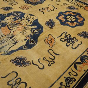 Yellow rug with large blue figural motifs and coral clouds resting on worn wood floors.