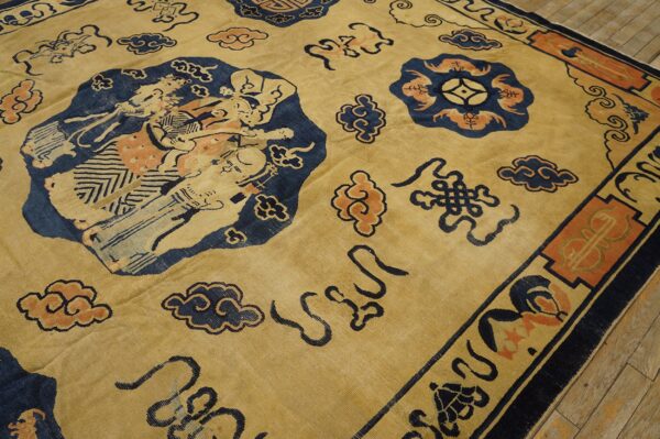 Yellow rug with large blue figural motifs and coral clouds resting on worn wood floors.