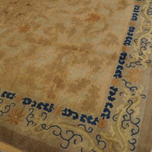 A tan floral rug features a contrasting blue and yellow scroll border on distressed wooden planks.