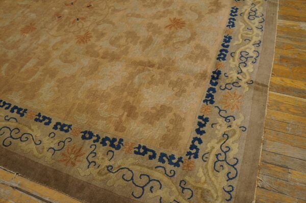 A tan floral rug features a contrasting blue and yellow scroll border on distressed wooden planks.