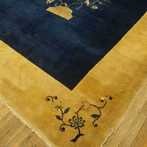 A deep blue rug field with gold floral patterns meets a wide golden border on worn wood planks.