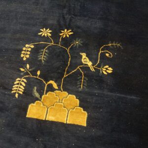 Plush navy blue rug featuring a yellow pictorial design of a bird, branches, and stylized rock formations.