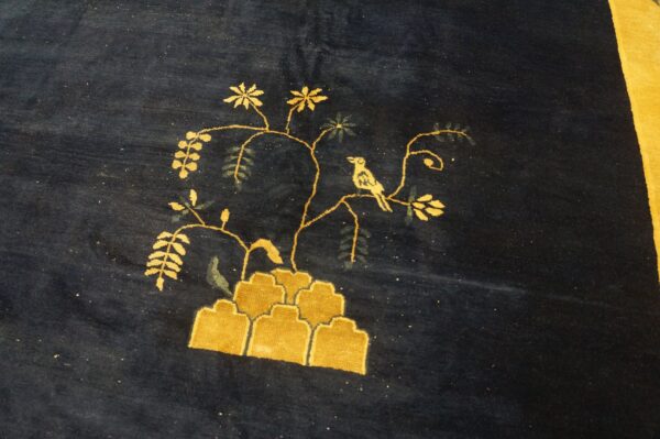 Plush navy blue rug featuring a yellow pictorial design of a bird, branches, and stylized rock formations.