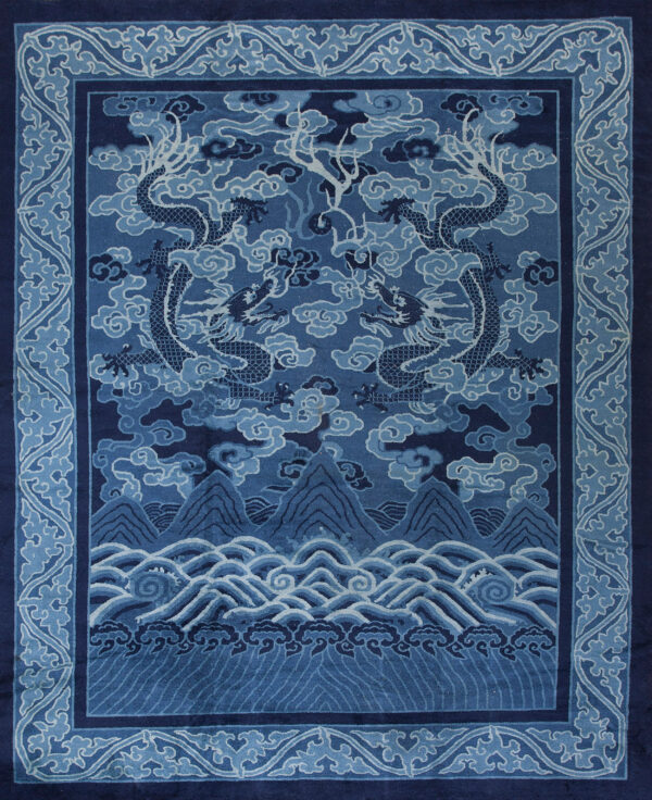 A dark blue rug featuring two dragons flying over mountains and waves, surrounded by a cloud border.