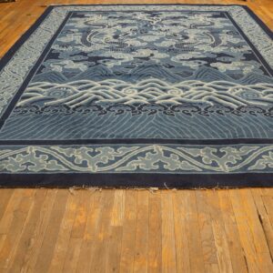 A large blue rug featuring dragons, clouds, mountains, and waves rests on rustic hardwood flooring.