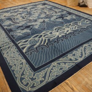 Intricate blue and white dragon and wave pattern rug displayed on distressed hardwood flooring.