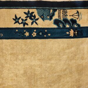 Tan rug detail with dark teal borders framing a field pattern of flowers, buildings, and a boat.