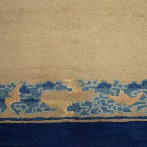 A beige rug field transitions to a decorative border featuring blue cloud shapes and a solid dark blue band.