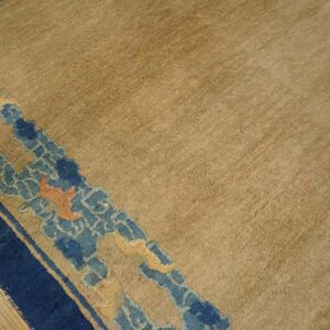 Textured beige rug field detailed with a stylized navy and pale blue border on wood planks.