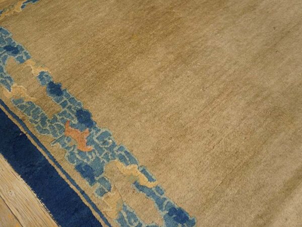 Textured beige rug field detailed with a stylized navy and pale blue border on wood planks.