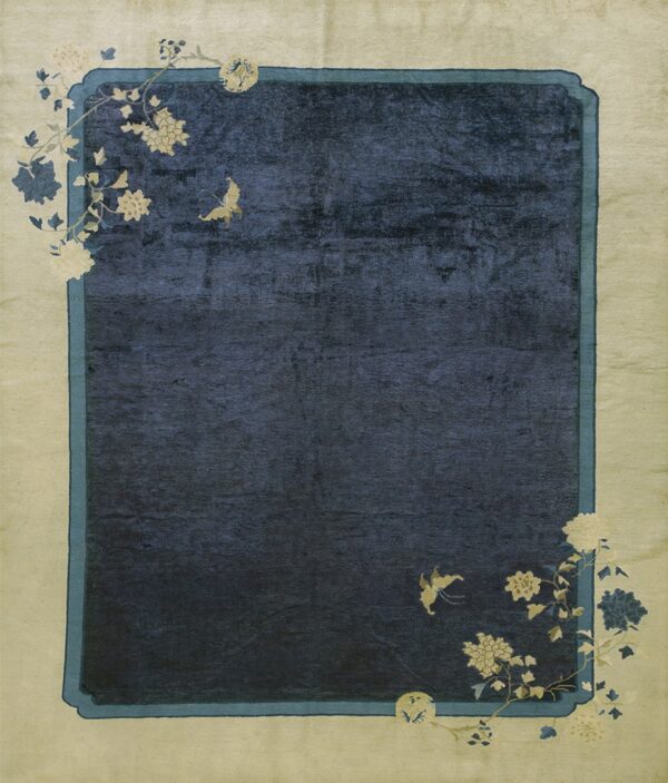 Rectangular rug with a navy center field bordered in light gold, featuring curving floral and butterfly designs.