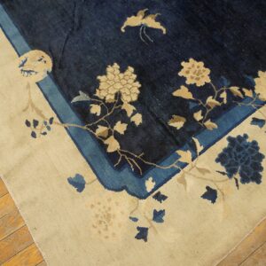 Deep blue rug with an ivory border features beige and light blue floral designs on wooden floors.