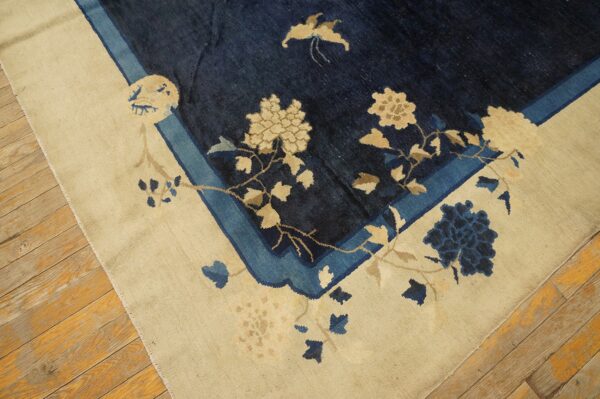 Deep blue rug with an ivory border features beige and light blue floral designs on wooden floors.