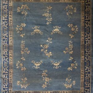 The rug is slate blue with scattered tan floral sprays and intricate blue and beige borders.